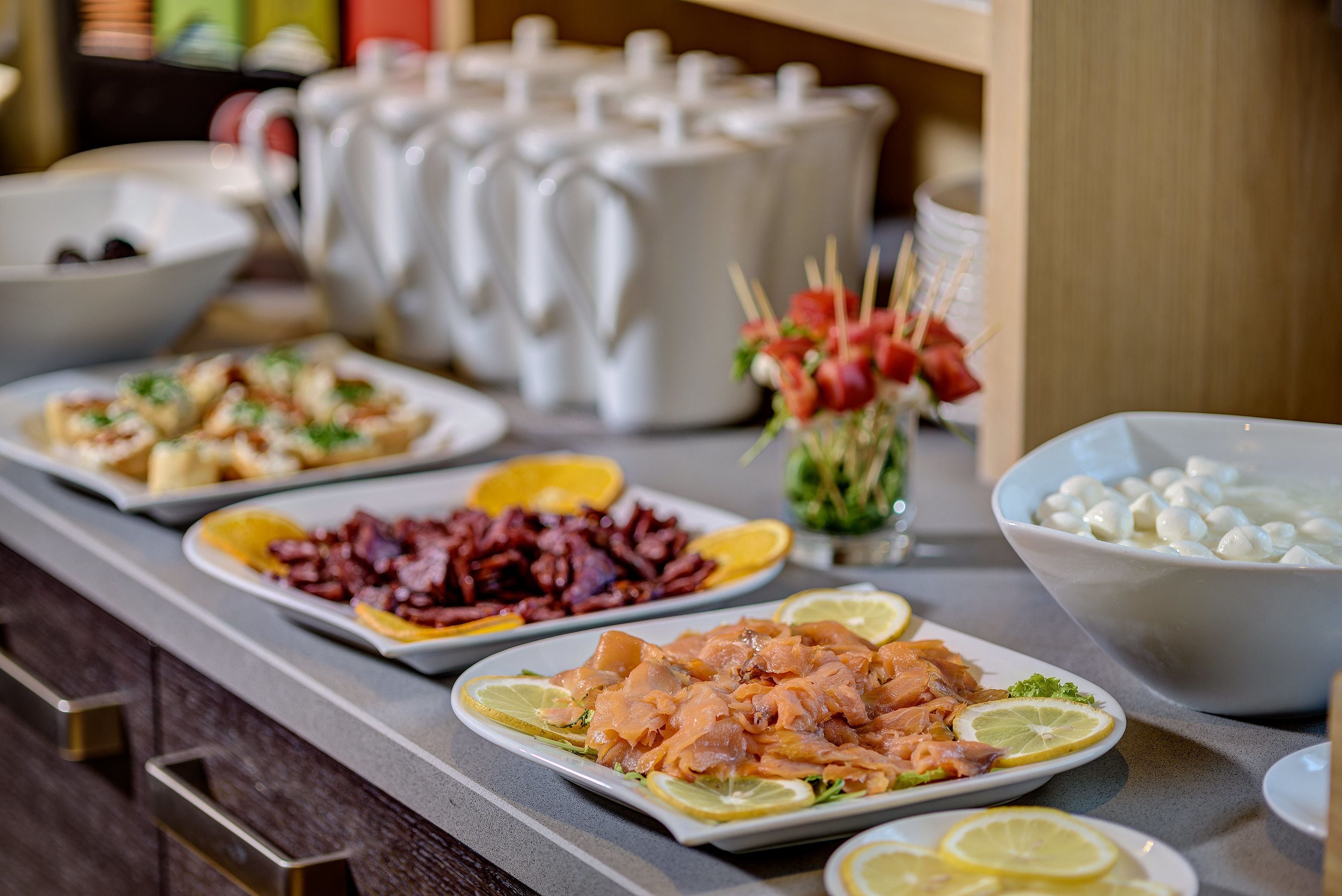 Een buffet met diverse gerechten, waaronder zalm, rood vlees en een schaal eieren.
