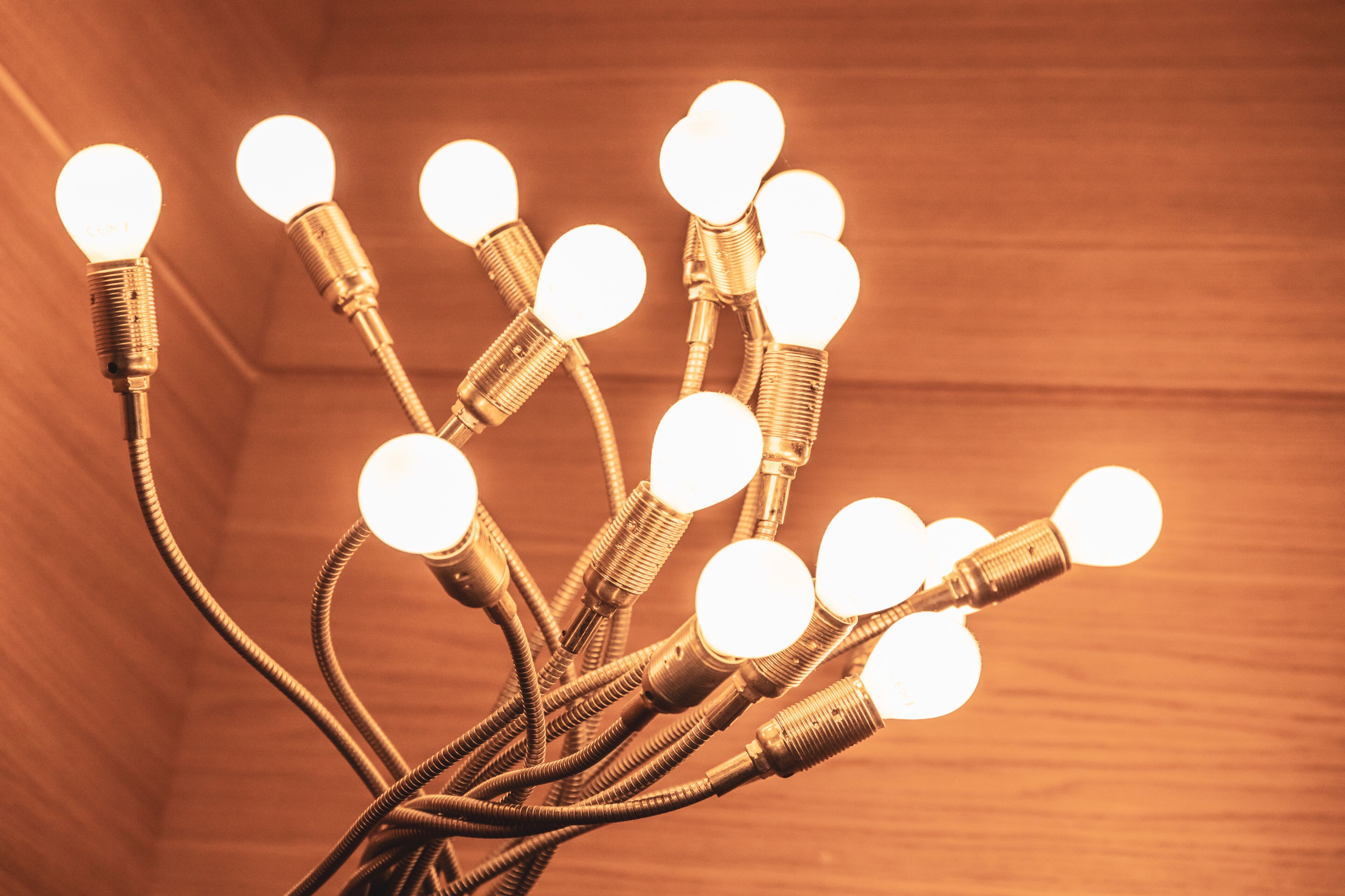 A cluster of light bulbs with exposed wires, set against a wooden background.