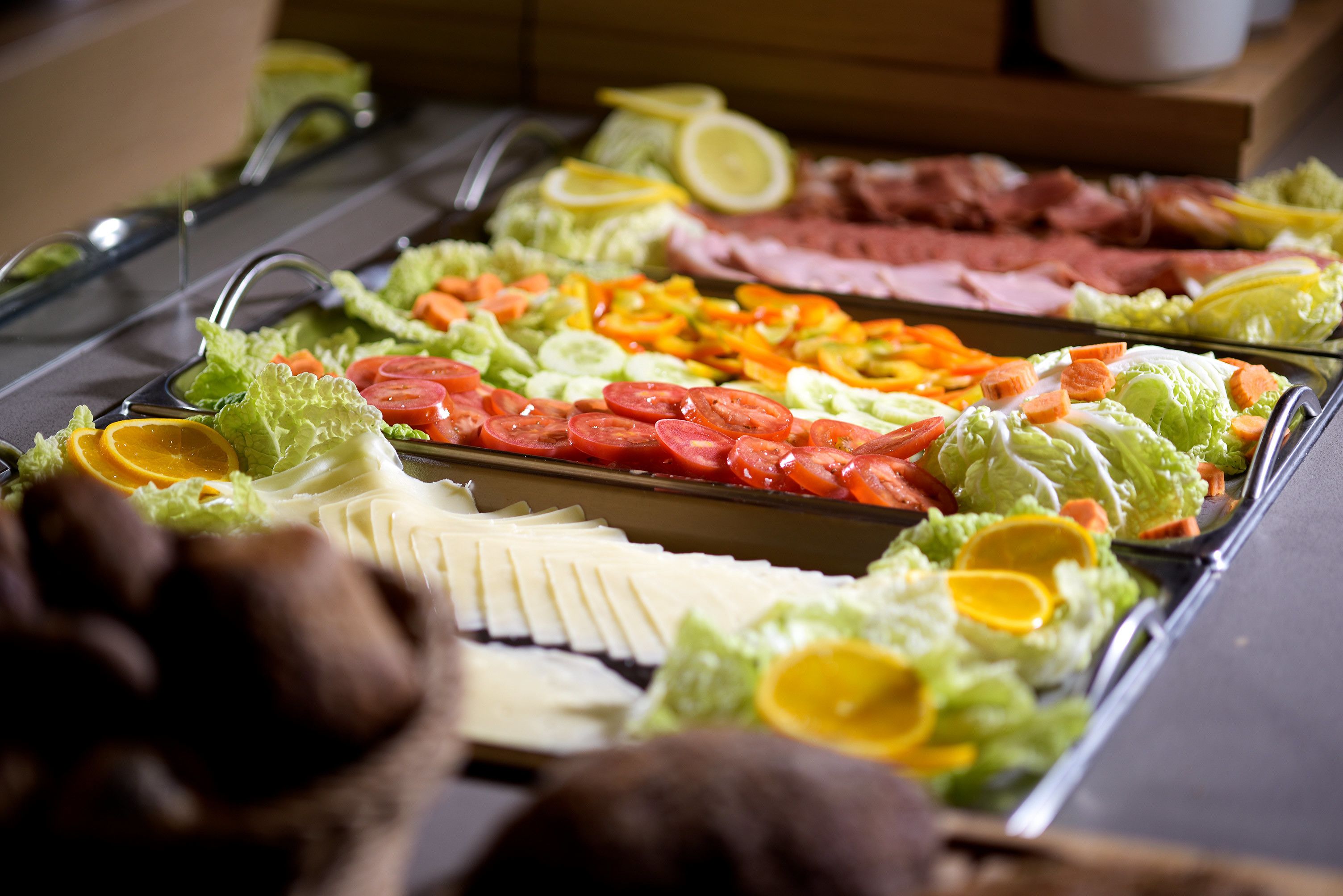 A buffet with various food items including meats, vegetables, and garnishes.