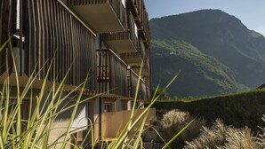 A modern building with a balcony overlooking a lush valley. - Art & Design Hotel Napura (Terlano)
