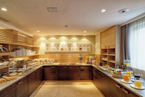 A modern breakfast buffet with wooden cabinets, a variety of food options, and a coffee station. - Art & Design Hotel Napura (Terlano)
