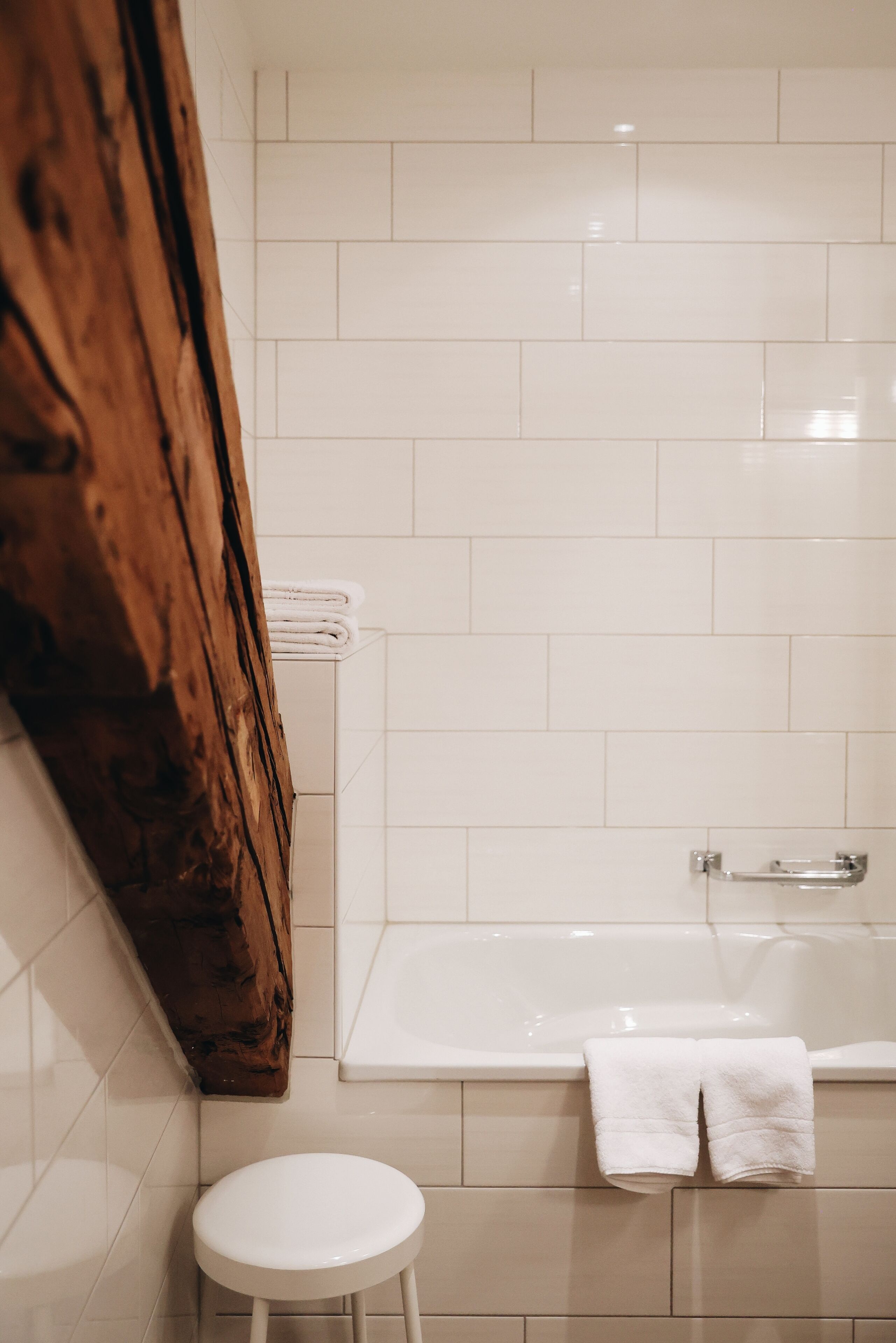 A bathroom with a white bathtub, a wooden door, and a white toilet.
