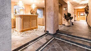 Un vestíbulo con mostrador de recepción, una escalera y un pasillo que conduce a una zona de cocina.