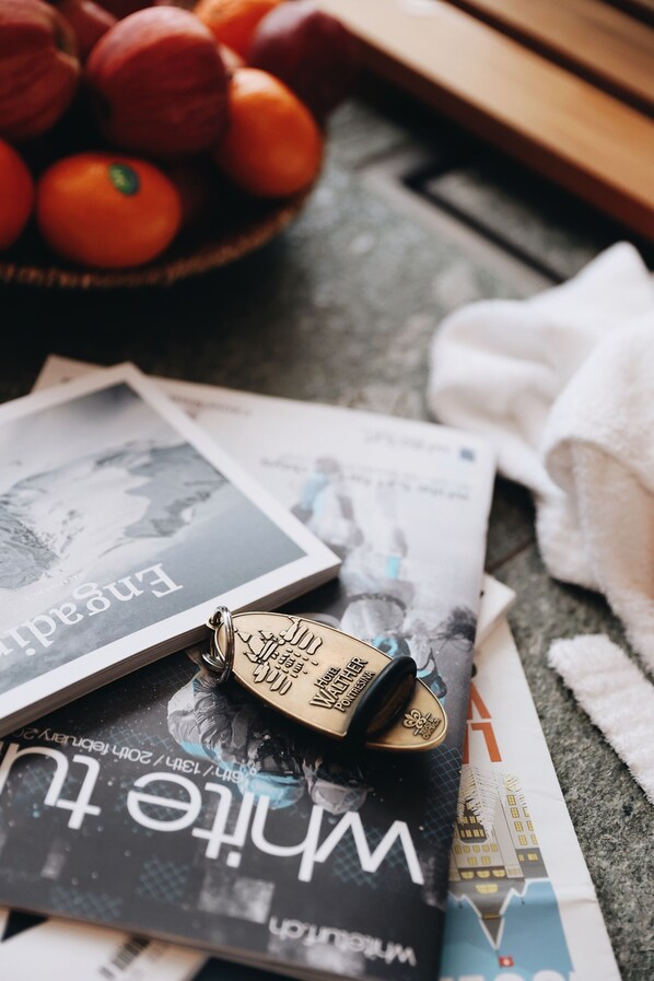 A magazine, a coin, and a bowl of oranges on a table. - Hotel Steinbock (Pontresina)