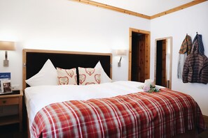 Ein Hotelzimmer mit einem großen Bett, zwei Nachttischen, einem Holz-Kopfteil und einem Kleiderständer mit Jacken.