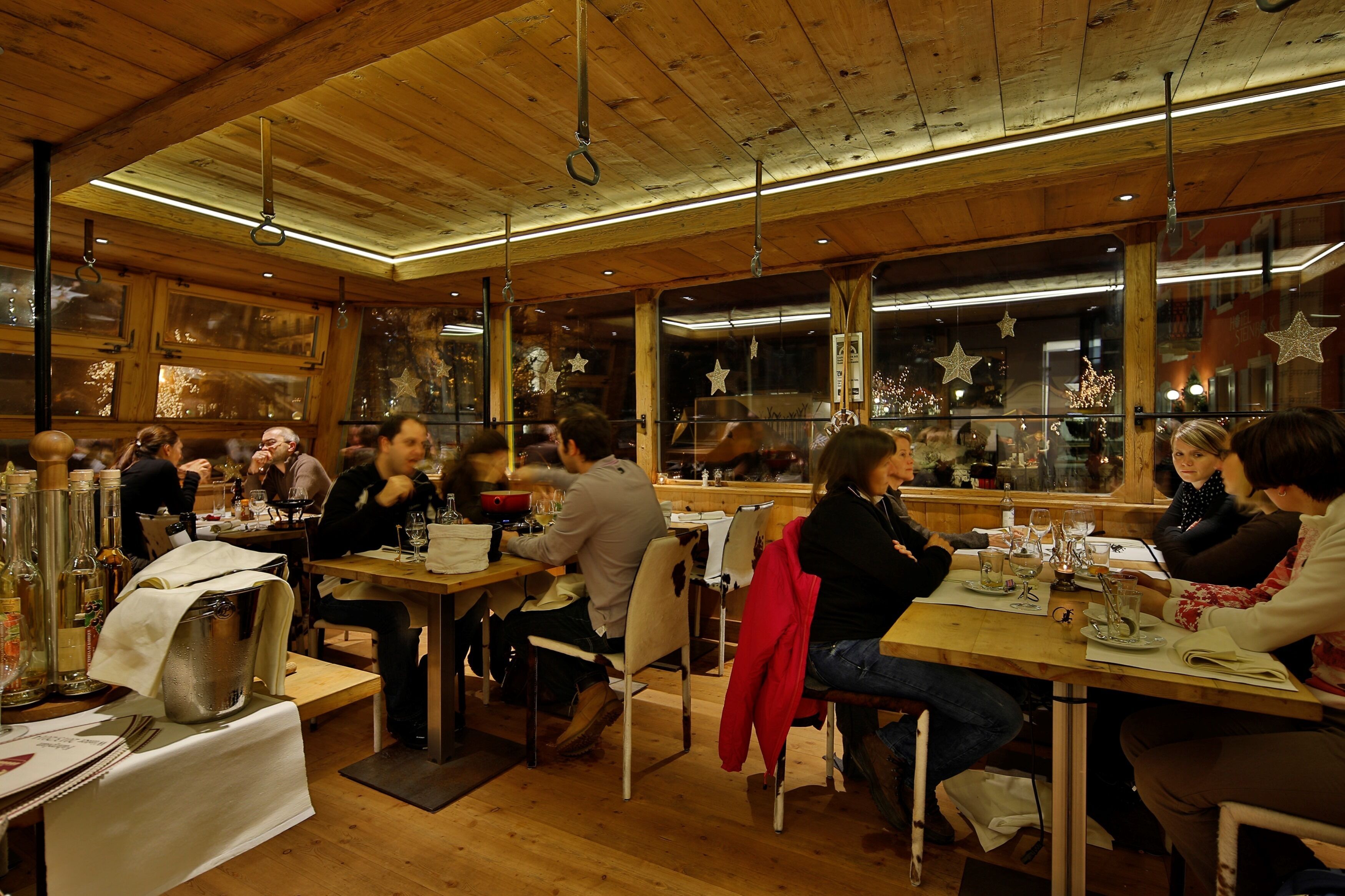 Un restaurant au décor intérieur en bois, avec des tables dressées, nappées, et où les clients sont en train de dîner.