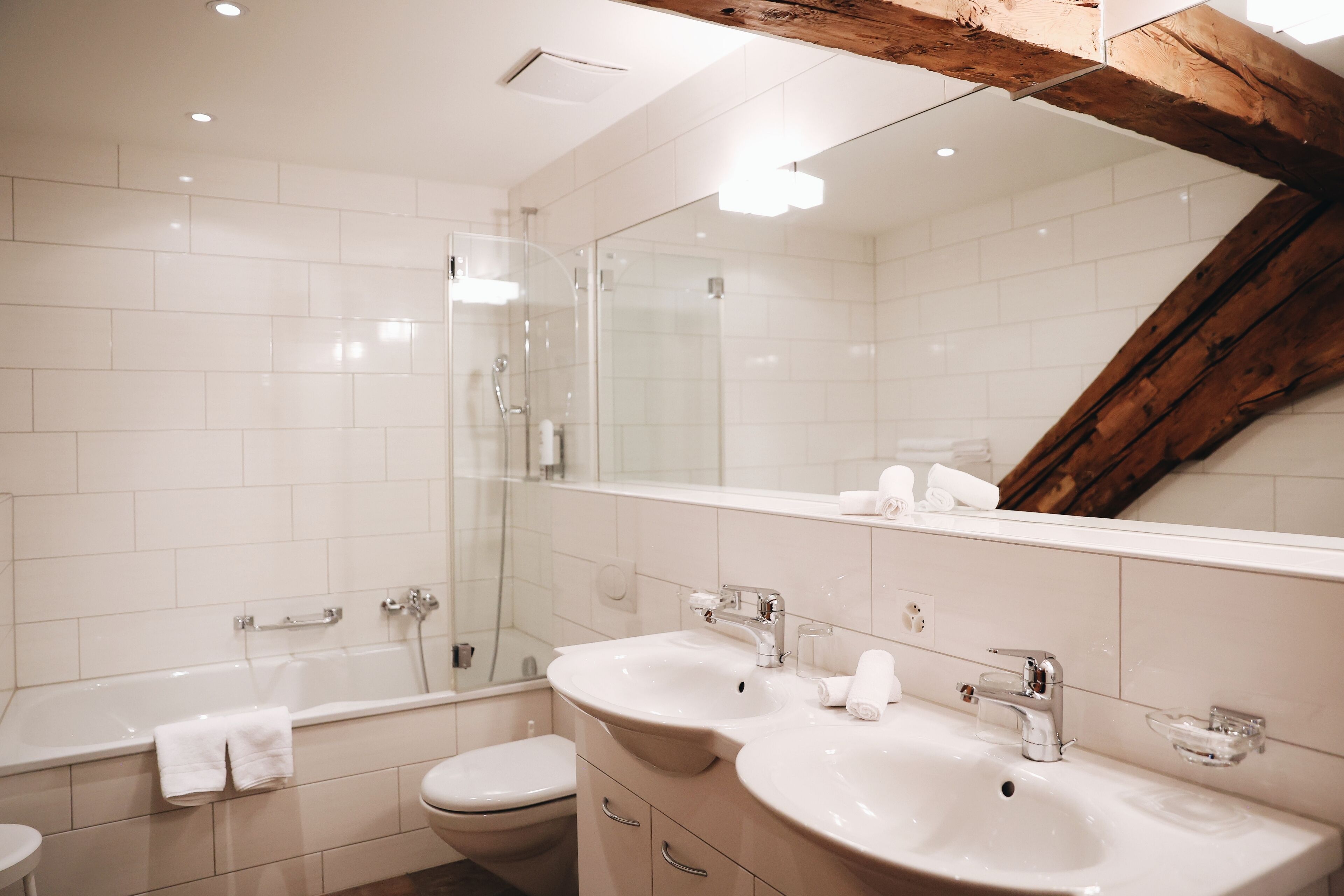 A modern bathroom with a glass shower enclosure, a double sink vanity, and a large mirror.