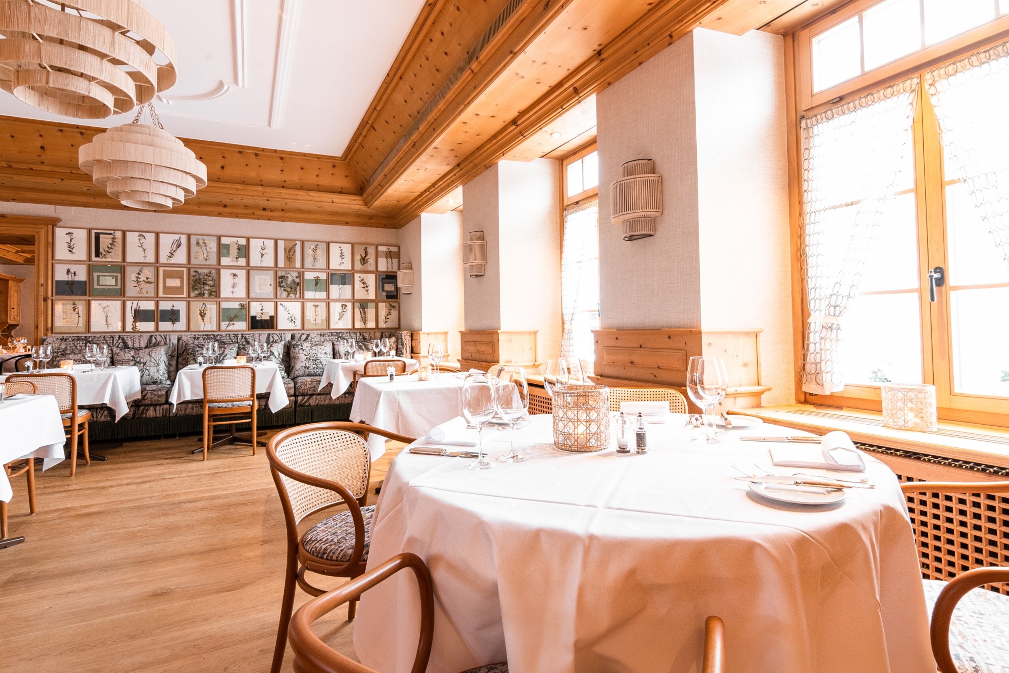 Un restaurant au décor intérieur en bois, avec des nappes blanches et des œuvres d’art encadrées accrochées aux murs.