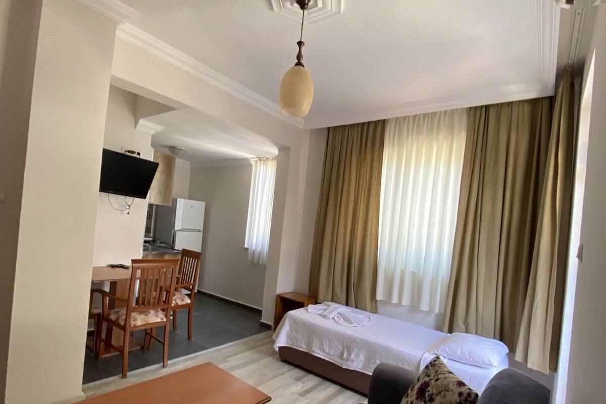A hotel room with a bed, a sofa, a dining table, and a TV.