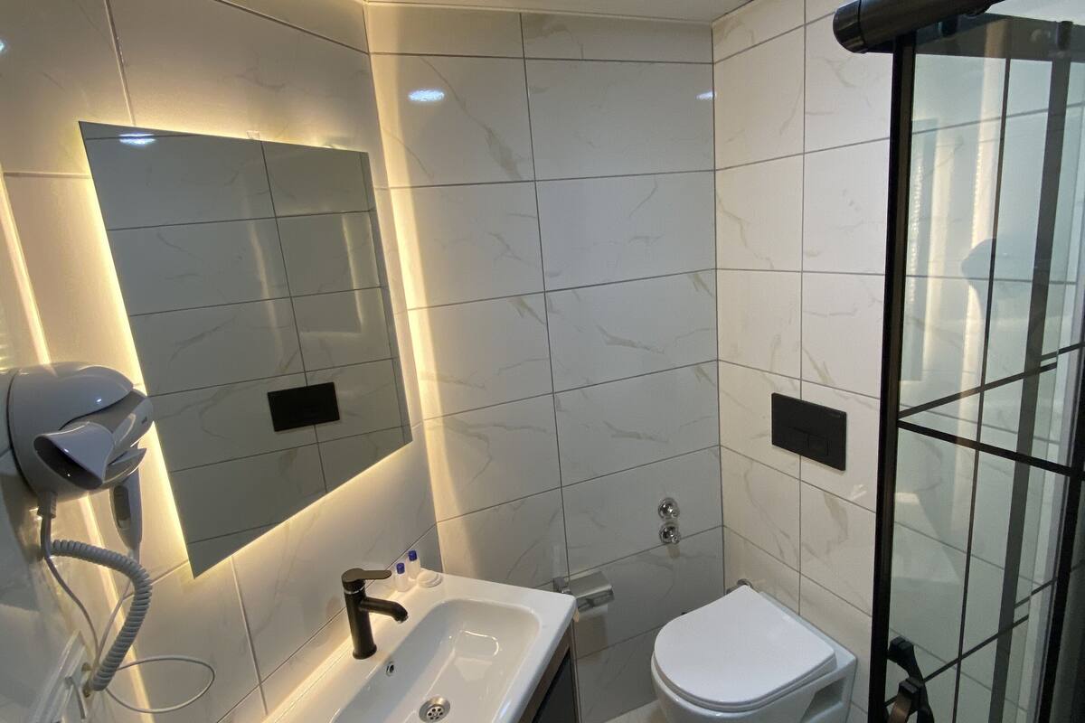 A modern bathroom with a vanity, sink, mirror, and toilet.