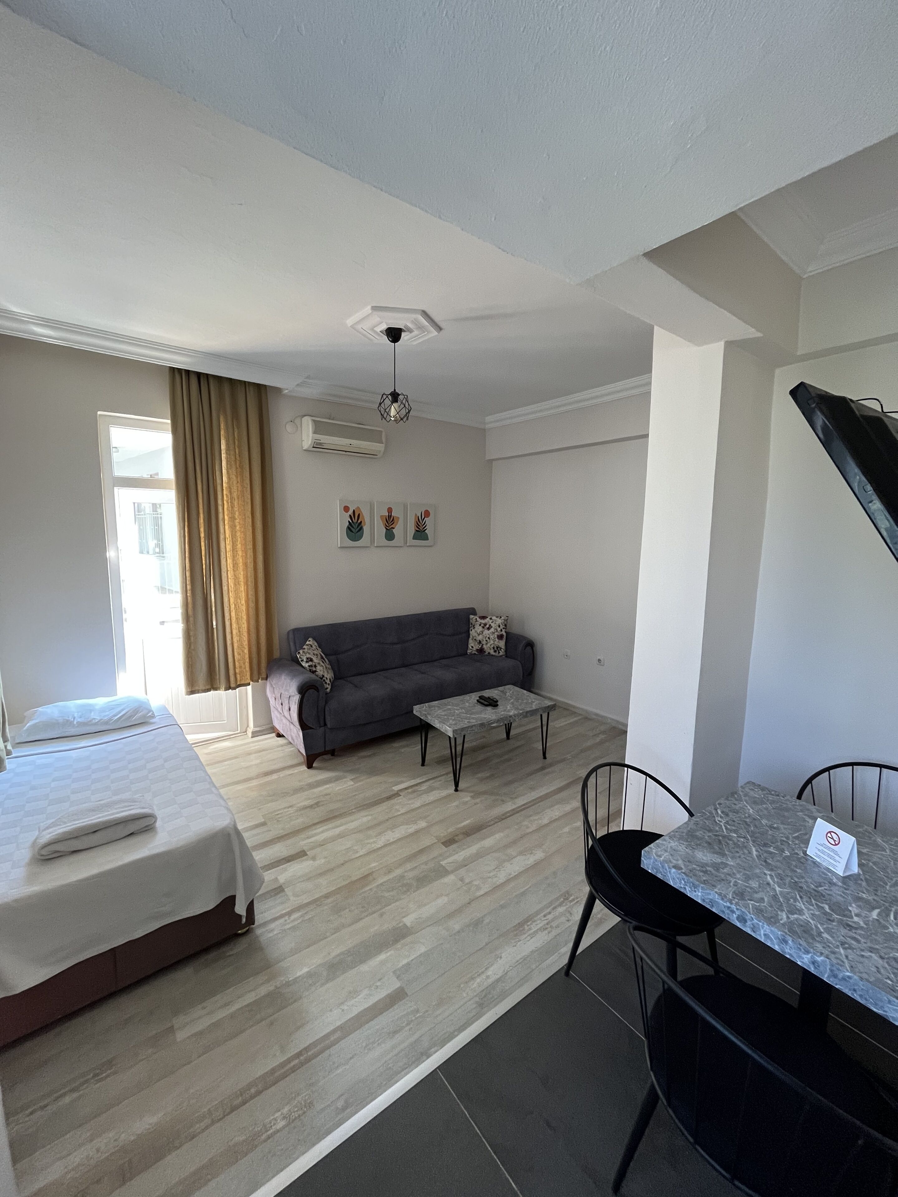 Una habitación de hotel moderna con cama, sofá, mesa de comedor y ventilador de techo.