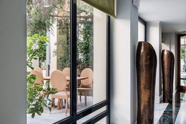 Un interior moderno con una pared de vidrio, muebles de mimbre y altas columnas cilíndricas.
