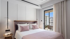 Un dormitorio moderno con una cama grande, una mesita de noche de madera y vistas a la ciudad desde un balcón.