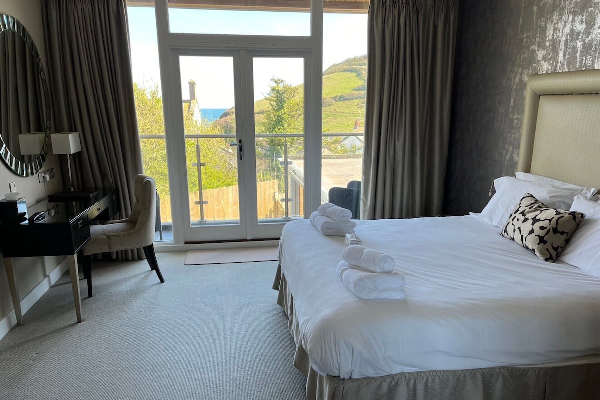 A hotel room with a bed, a desk, a chair, and a view of the outdoors.