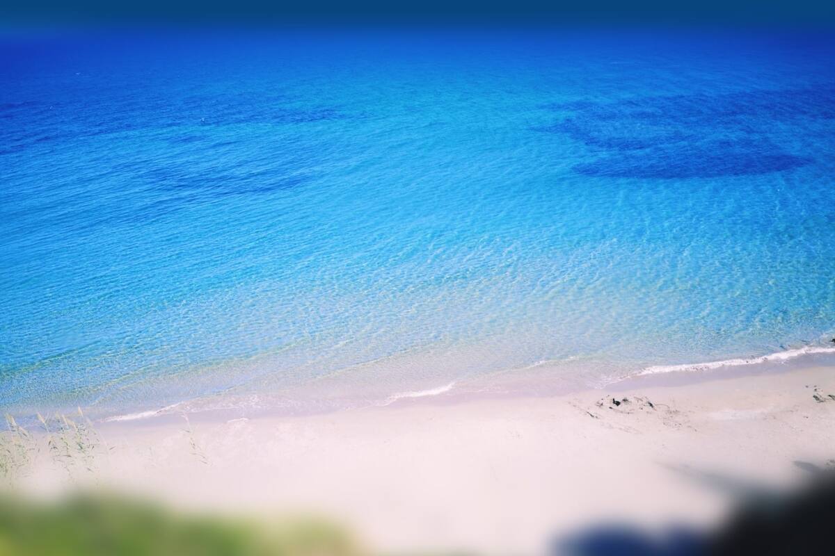 A beach with clear blue water and white sand.