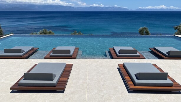 A poolside area with lounge chairs and a view of the ocean. - Colonides Beach Hotel (Pylos-Nestoras)