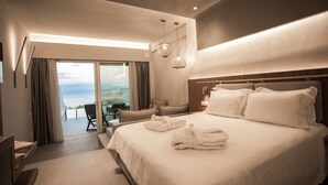 A modern hotel room with a large bed, a balcony with a view, and a dining area. - Colonides Beach Hotel (Pylos-Nestoras)