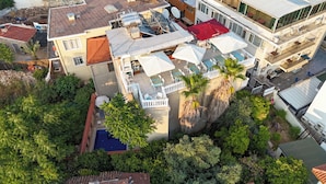 Vista aérea de un edificio residencial con terraza en la azotea, paneles solares y piscina.