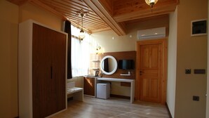 Una habitación con un armario de madera, un escritorio con espejo, un refrigerador pequeño y un televisor en la pared.