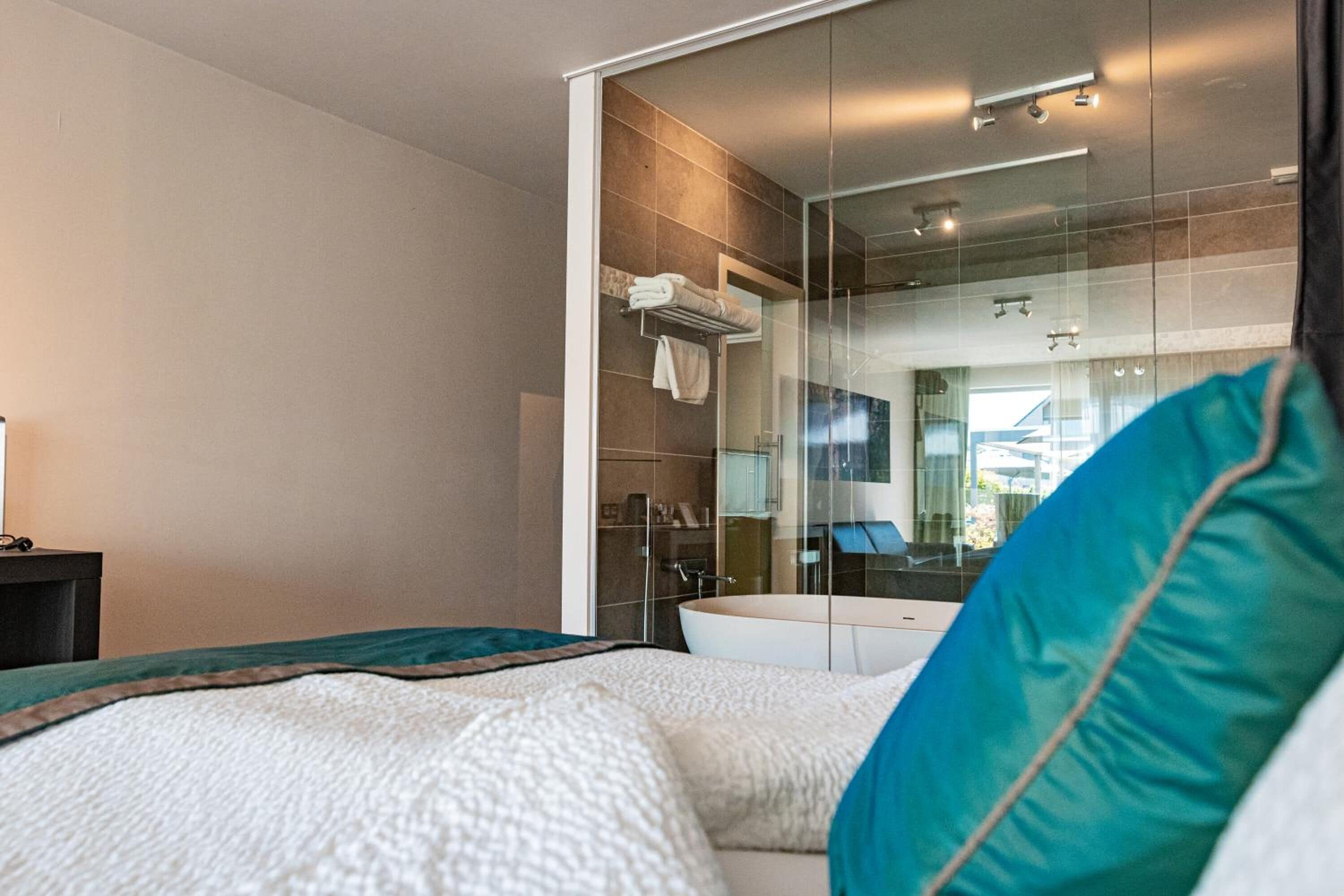 Habitación de hotel moderna con una cama grande, cabina de ducha de vidrio y vistas a la ciudad.