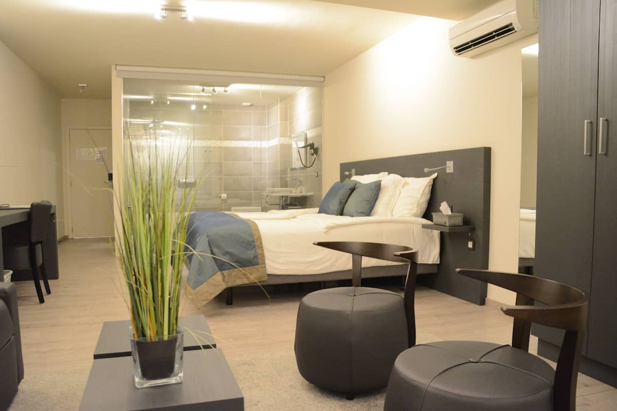 A modern bedroom with a bed, bedside table, and a potted plant.