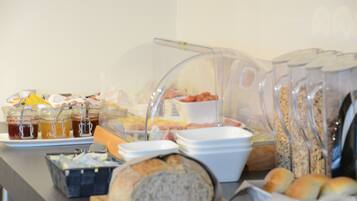 Un buffet proposant une variété de plats, notamment du pain, des pâtisseries et des condiments.