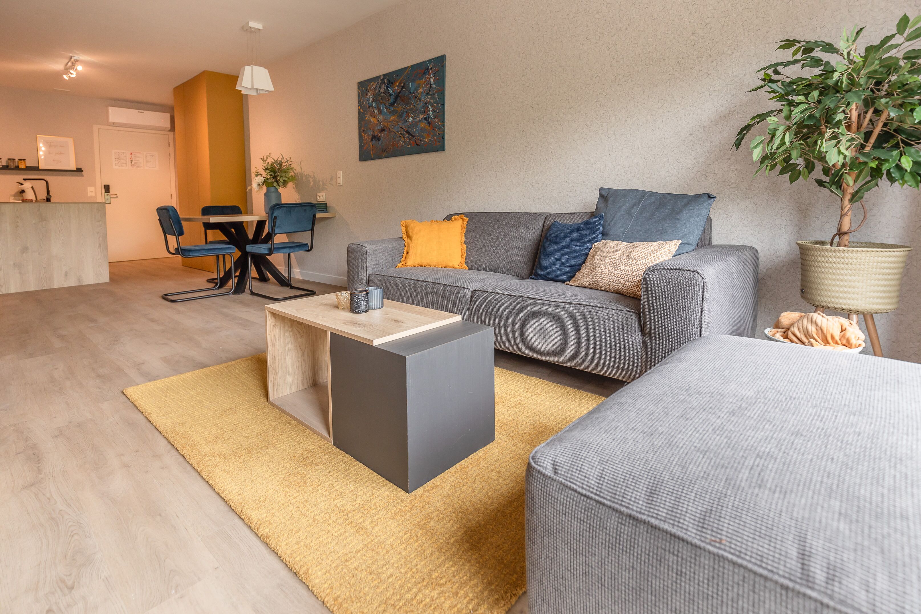 Un salon moderne avec un canapé gris, une petite table basse et un coin repas comprenant une table et des chaises.