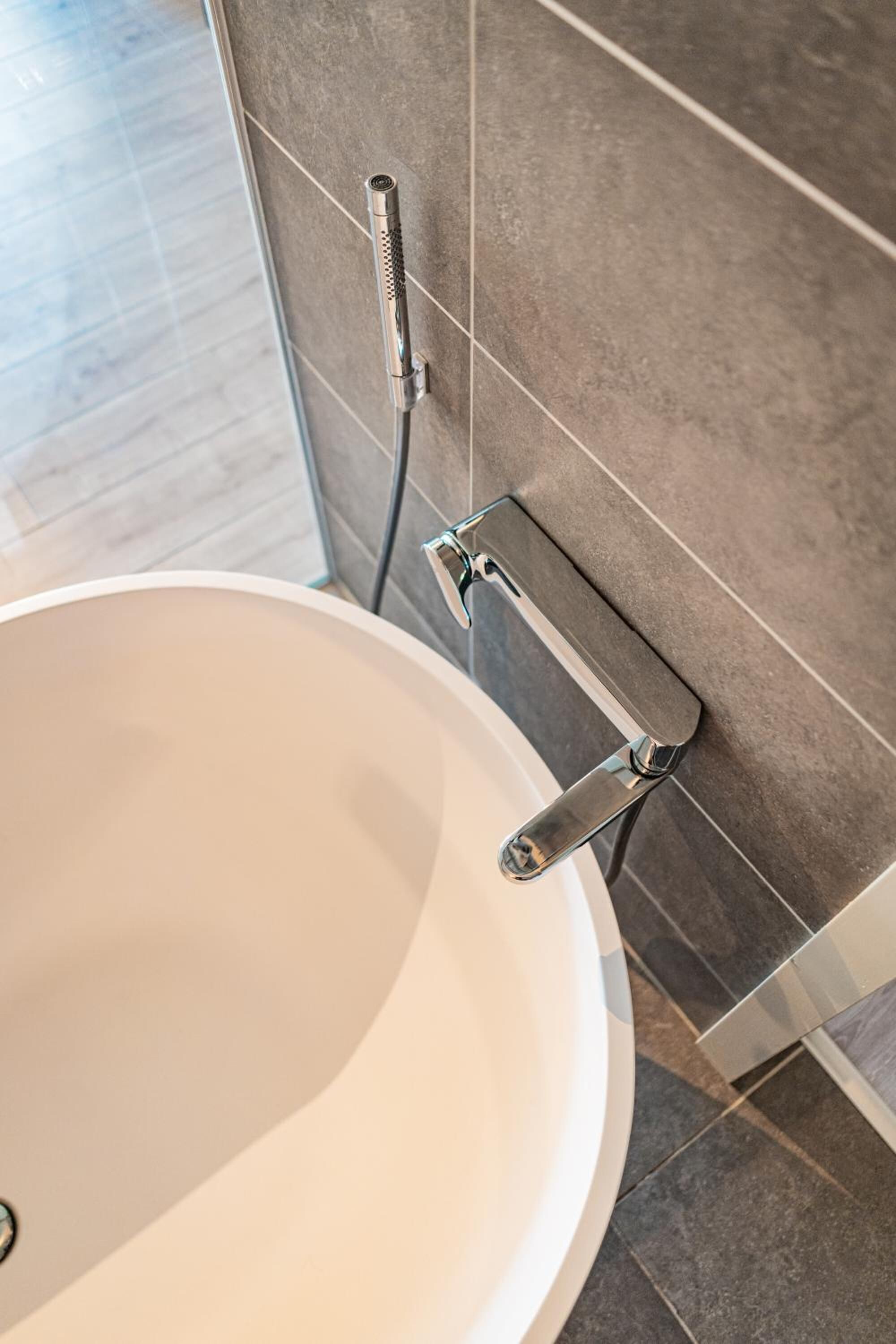 Een badkamer met een witte wastafel, een handdouche en een handdoekhouder aan de muur.