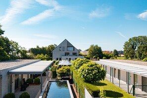 A modern building with a swimming pool, covered outdoor seating, and a well-maintained garden. - Abalona Hotel & Apartments (Dendermonde)