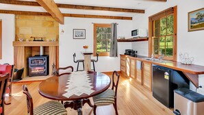 Una cocina acogedora con una mesa de madera, sillas, estufa empotrada y un fregadero.