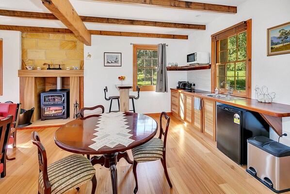 A cozy kitchen with a wooden table, chairs, a built-in stove, and a sink. - Blackwood Park Cottages (Mole Creek)