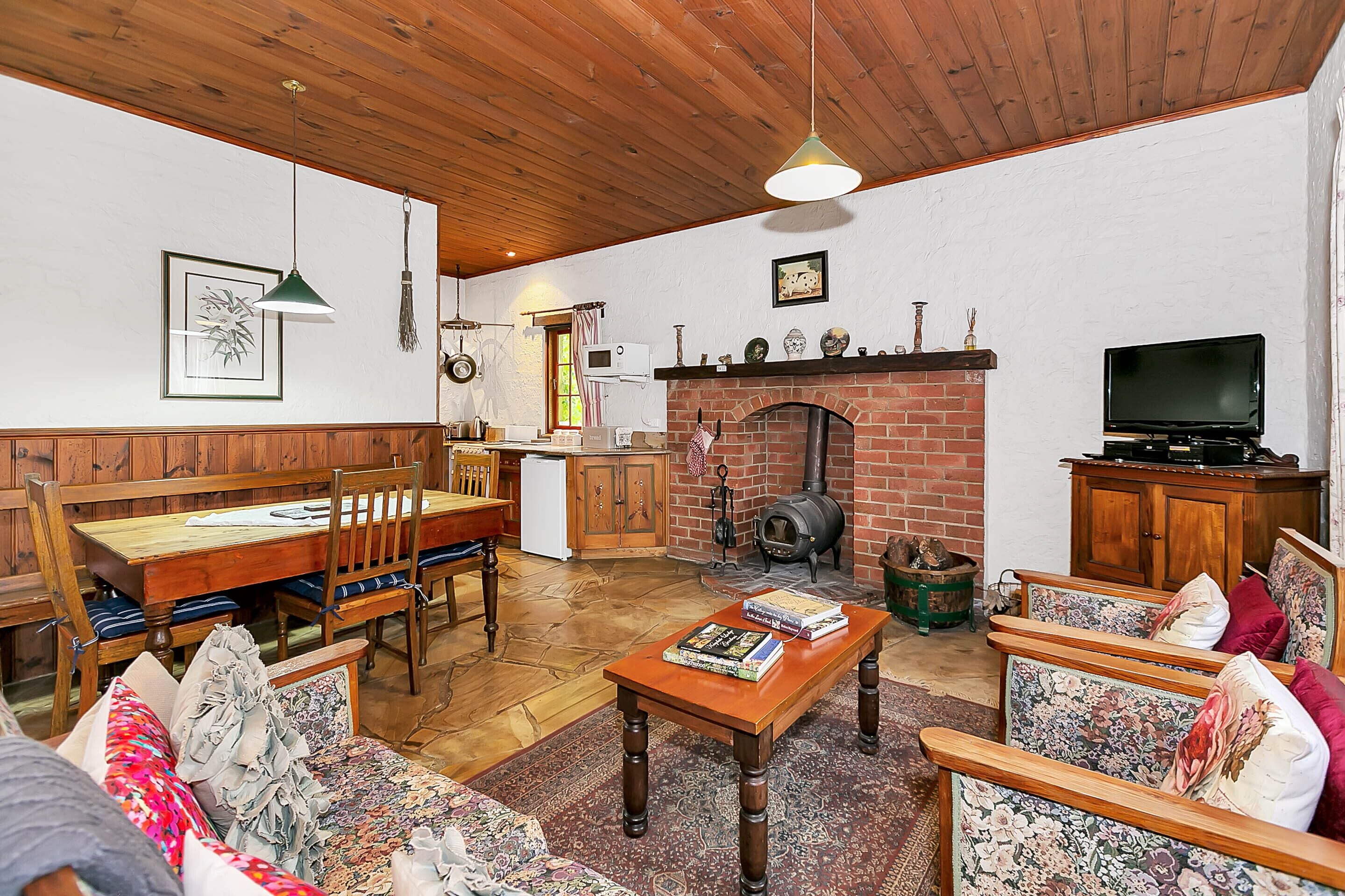 Ein gemütliches Wohnzimmer mit Kamin, Holzmöbeln und einem Fernseher.
