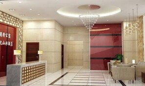 Eine Hotelhalle mit einer Rezeption, einem Kronleuchter und einer Sitzecke.
