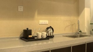 A kitchen with a sink, countertop, and a tray with a coffee maker, cups, and a kettle. - Century Landscape Hotel (Xi'an)