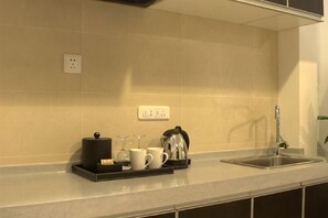 Eine Küche mit Spüle, Arbeitsplatte und einer Ablage mit Kaffeemaschine, Tassen und Wasserkocher.