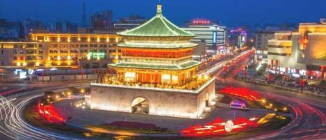 A traditional building with a green roof, surrounded by a roundabout with light trails indicating traffic.