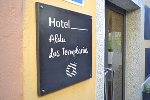 Señal del Hotel Alda Los Templiers, colocada sobre una pared amarilla.