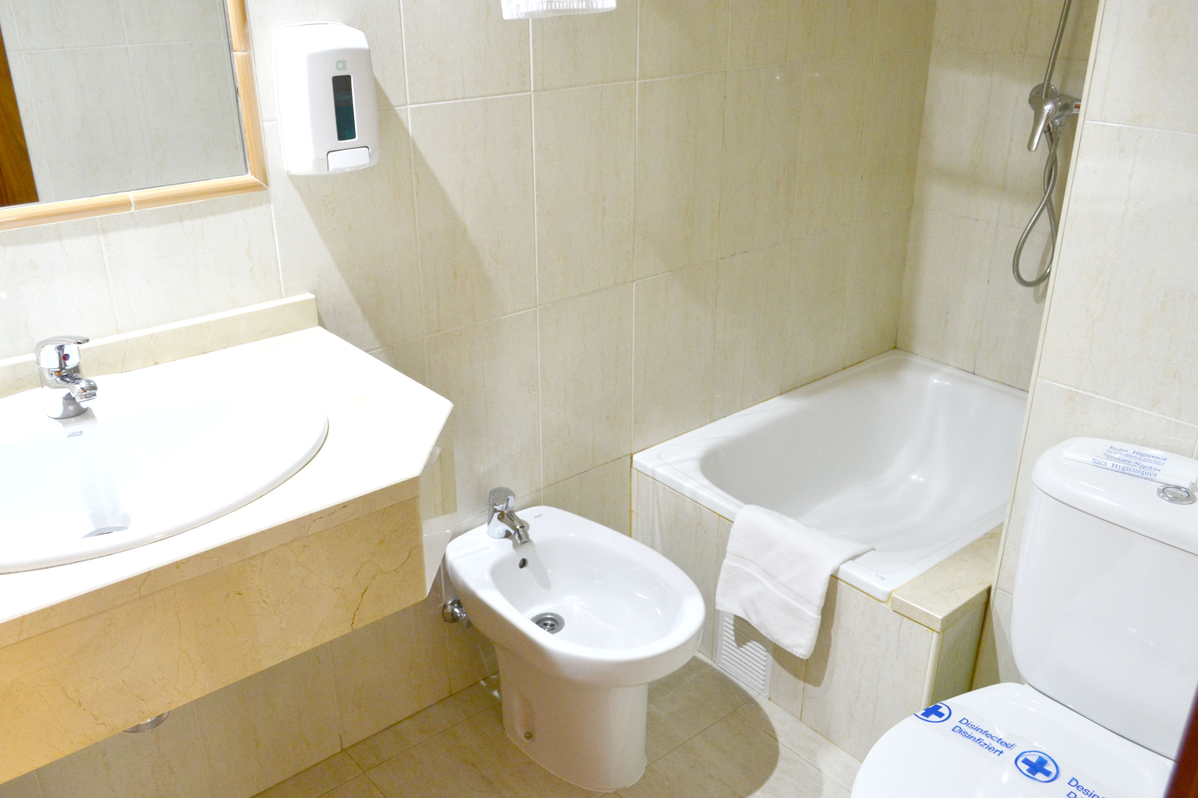 A bathroom with a sink, bidet, and bathtub.