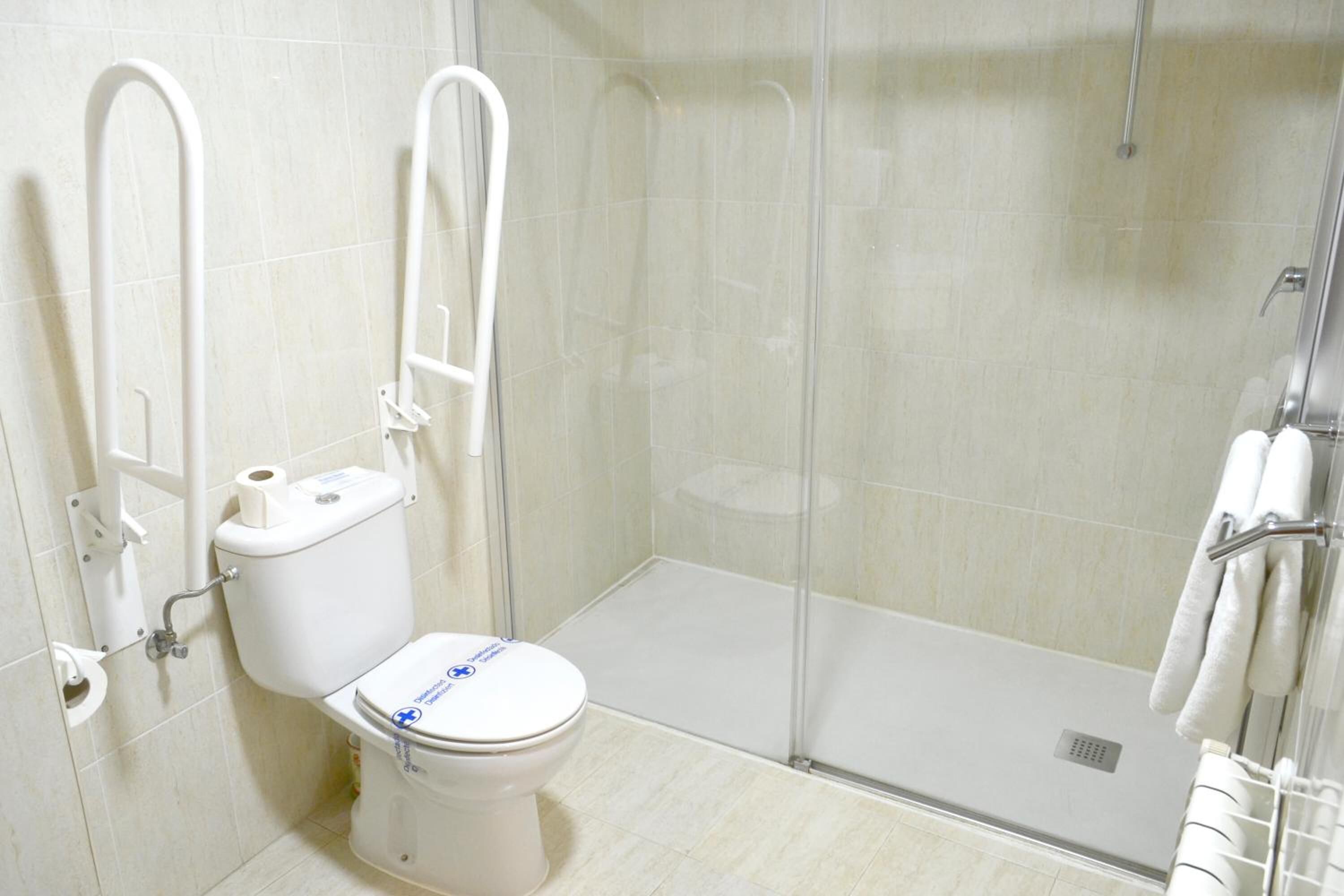 A bathroom with a toilet, a glass shower enclosure, and a towel rack.