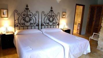 A double bed with a wrought iron headboard, two bedside tables with lamps, and a wooden wardrobe.