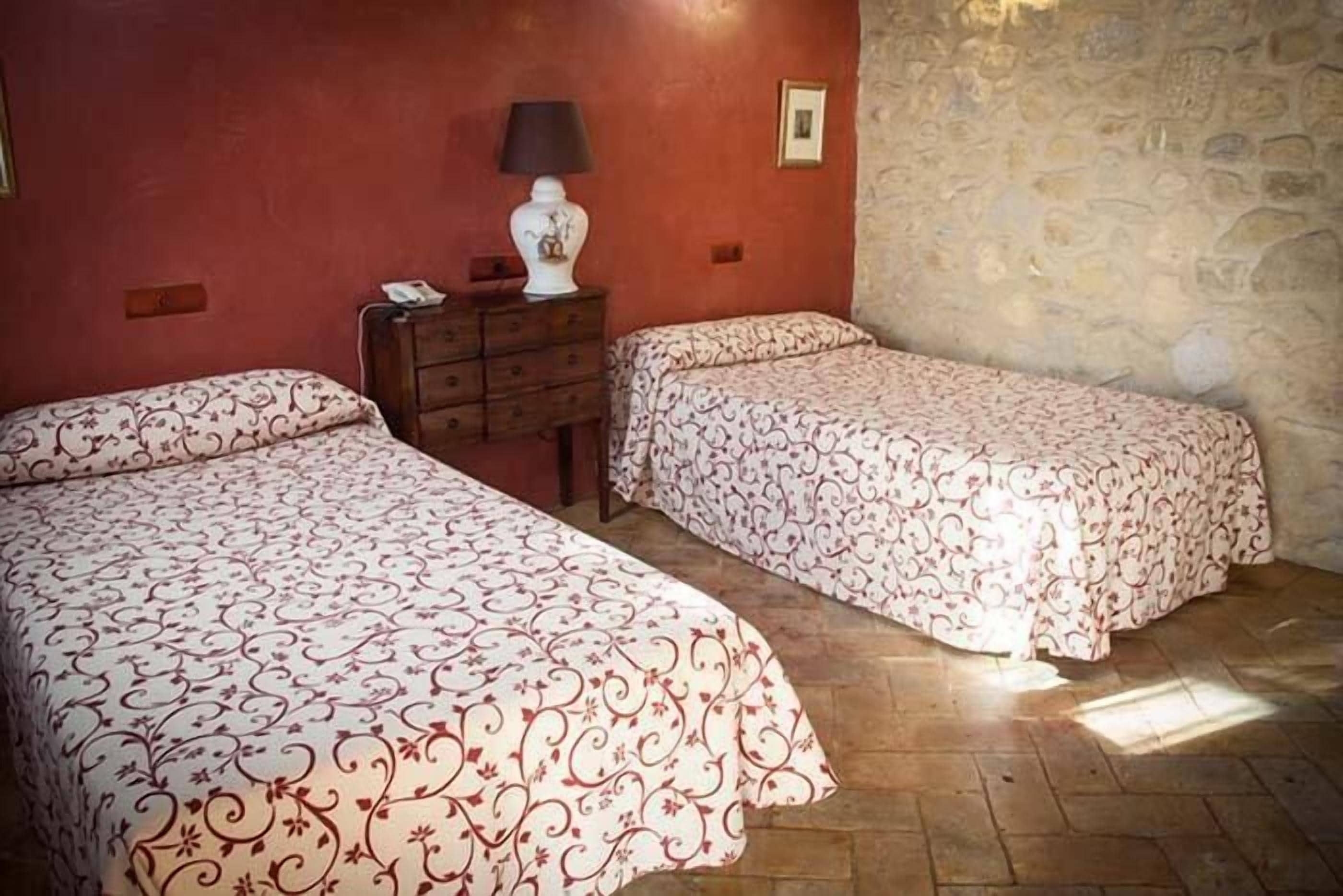 Een kamer met twee bedden, een kaptafel, een lamp en een stenen muur.