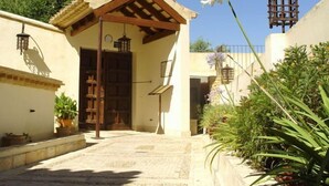 A courtyard with a covered entrance, a stone wall, and potted plants. - La Hospederia Del Monasterio (Osuna)