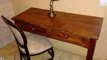 A wooden desk with a chair, a lamp, and a drawer.