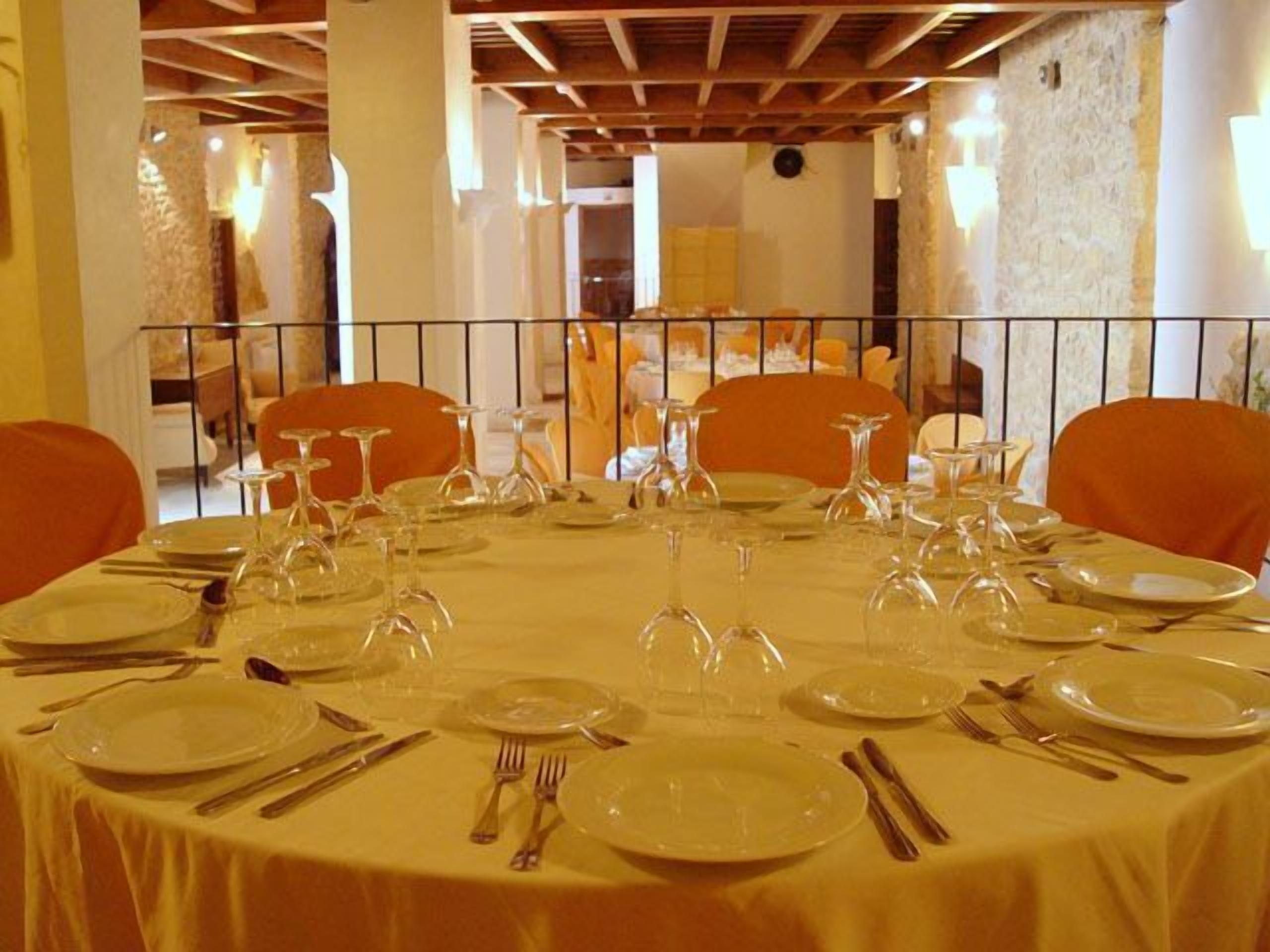 A round table set for a meal with chairs around it.