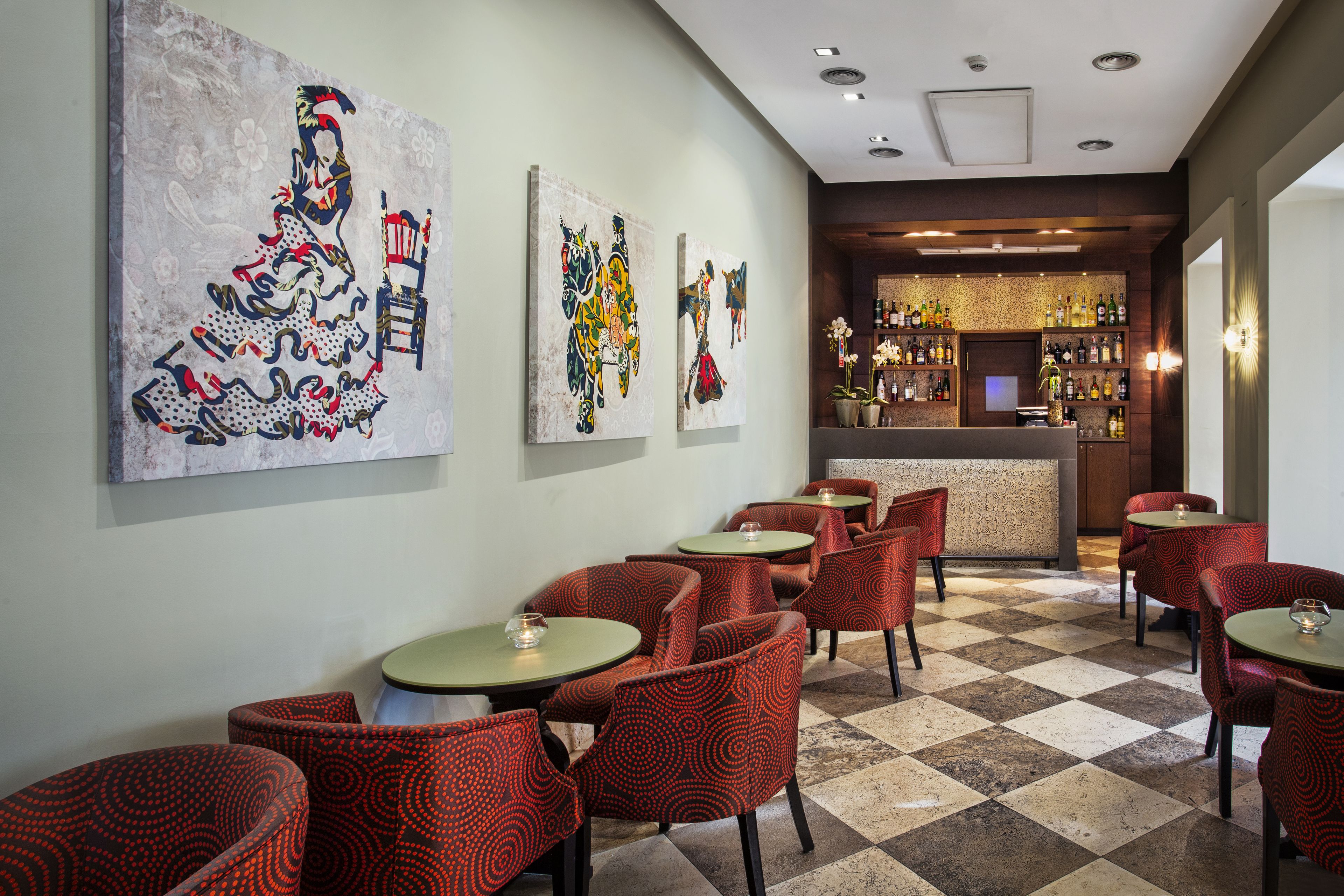 Un restaurant avec des chaises à motifs rouges, un sol à carreaux et un bar avec des étagères remplies de bouteilles.
