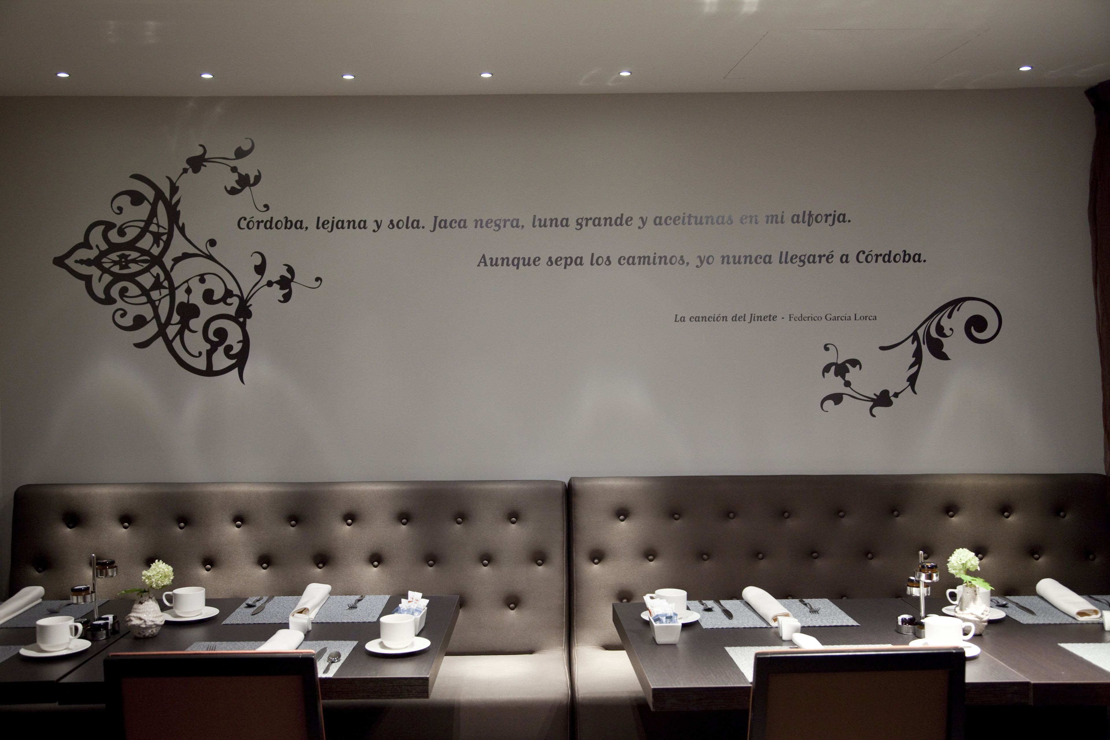 A restaurant interior with a high-backed booth seating area, tables set with white tableware, and decorative wall art.
