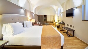 Habitación de hotel con una cama grande, un escritorio, una silla y un televisor.