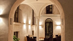 Un espacio interior con suelo de baldosas, una columna central y arreglos de asientos.