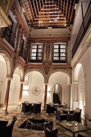 A spacious lobby with a high ceiling, ornate columns, and a checkered floor. There are multiple seating areas with tables and chairs. - Hotel Eurostars Patios de Córdoba (Córdoba)
