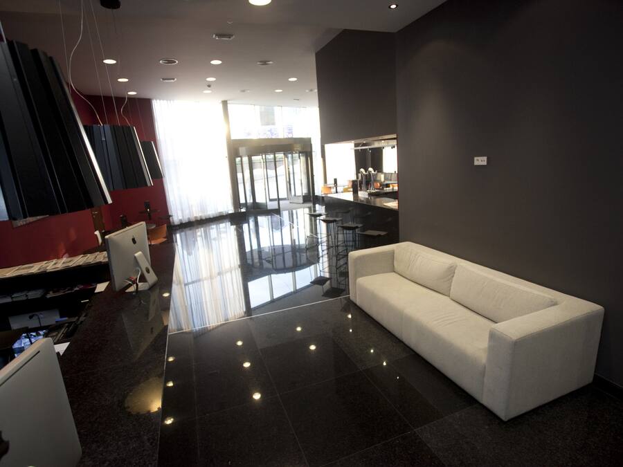 Ein modernes Interieur mit einem weißen Sofa, einem Glastisch und einer roten Akzentwand.